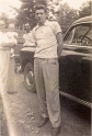 1900s Larry posing by his car, daughter in the background